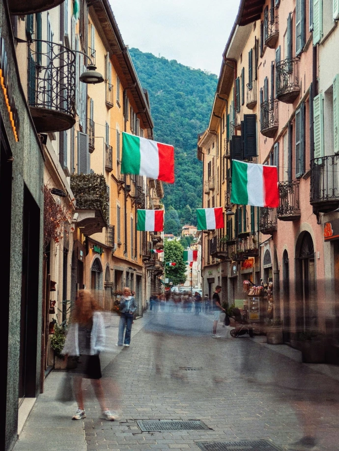 Italian flags hang above a bustling street.